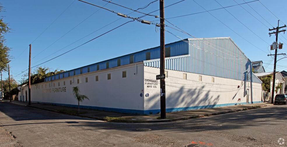 A large white building with a blue metal second floor, which reads "Giordano Furniture Mfg. Co." on its side.